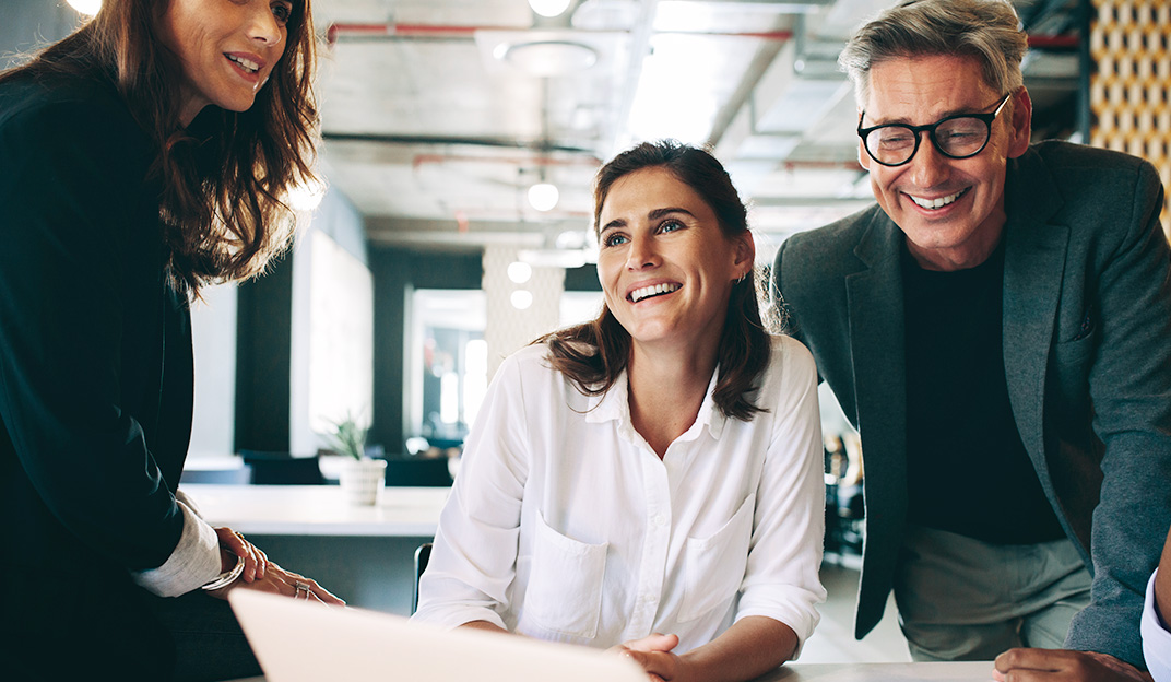 Due donne ed un uomo che sorridono parlando di un progetto